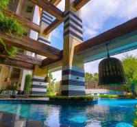A luxurious pool with wooden beams, surrounded by greenery, falls under the construction of apartments.
