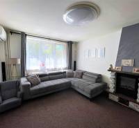 Living room with a fireplace, sofa, and armchair in a three-room apartment.