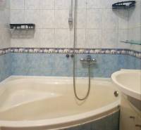 A bathroom with a corner bathtub and tiling in a 3-room apartment.