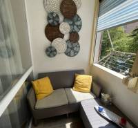 Balcony in a 3-room apartment with a comfortable sofa and wall decoration.
