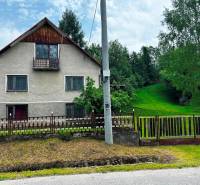 A family house in Veľká Lesná with a landscaped garden and lawn, surrounded by trees.