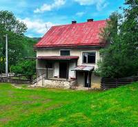 A family house in Veľká Lesná with a red roof and a garden surrounded by greenery.