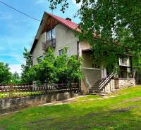 A family house in Veľká Lesná surrounded by greenery and a wooden fence.