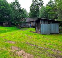 A family house in Veľká Lesná with a wooden shelter surrounded by greenery and trees.