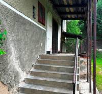 Entrance with a staircase to a family house in Veľká Lesná, surrounded by green vegetation.