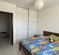 Bedroom with a double bed, built-in wardrobe, and lamp in a 3-room apartment.