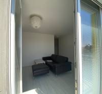 Living room with a sofa in a 3-room apartment, view through open balcony doors.