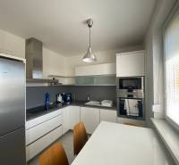 A kitchen in a 3-room apartment with white furniture and appliances, dining table.