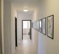 A hallway in a 3-room apartment with light floors and pictures on the walls.
