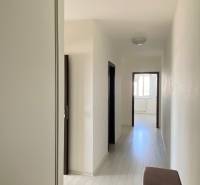 A hallway in a 3-room apartment with white walls, doors leading to rooms.