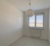 A room in a 3-room apartment with white walls, a hanging lamp, and a window.