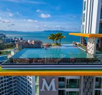 Apartment construction in Pattaya with a rooftop pool and sea view.