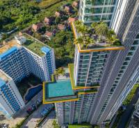 The construction of apartments in Pattaya features a high-rise building with a pool and a rooftop garden.