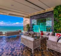 Apartment construction with terrace and sea view in Pattaya, comfortable seating and greenery.
