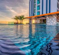 Infinity pool under construction in an apartment building in Pattaya, at sunset with palm trees in the background.