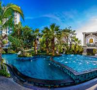 The construction of apartments in Pattaya includes a pool with greenery and palm trees.