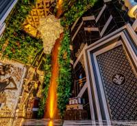 Luxurious interior with a large chandelier, mirrored wall, and green decorations in apartment construction.