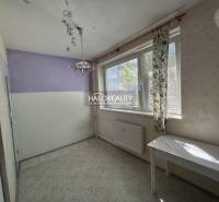 A room in a studio apartment with a purple wall and a white table under the window.