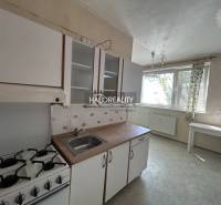 A kitchen with a stove and a sink in a studio apartment, bright furnishings, large window.