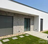 A family house in Turany with a stone facade, windows with shutters, and a well-maintained lawn.
