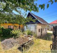A family house in Banská Bystrica, surrounded by greenery and an older fence.