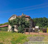 A family house in Lovinobaňa with a garden, gate, and greenery on a slope.