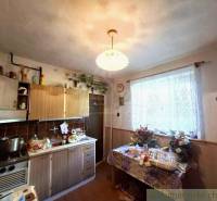 A kitchen in a family house with a countertop, a table, and flowers on the window.