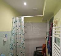 Bathroom in a family house with a bathtub, curtain, and plastic chair.