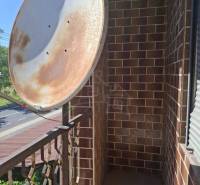 A balcony of a family house in Lovinobaňa, with a metal railing and a satellite dish.