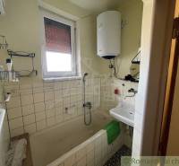 A bathroom in a family house with a shower, a sink, and a water heater.