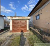 A garage at a family house in Nové Zámky with an older fence and a blue sky.