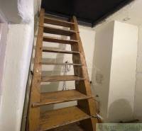 Stairs leading to the attic in a family house, wood and white walls.