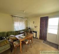 Living room in a family house with a sofa, table, chairs, and decorated curtains.