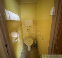 A small bathroom with a toilet in a family house, yellow walls and wooden floor.