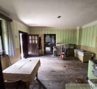 Interior of a family house with wooden flooring, antique furniture, and a simple table.