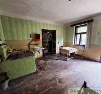 A kitchen in a family house with simple furnishings, wooden floor, and green walls.
