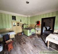 A traditional kitchen of a family house with a tiled stove and period furniture.
