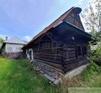 A family house in Pohorelá with an old wooden house and a grassy garden.