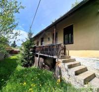 A family house in Pohorelá with a wooden terrace, stairs, and a grassy plot with flowers.