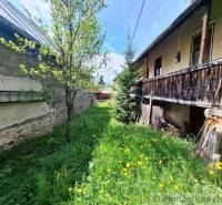 A family house in Pohorelá, a grassy yard with flowers and trees, a wooden veranda.