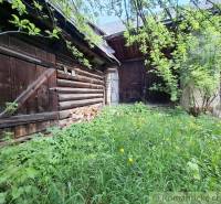 Wooden structures and an overgrown garden at a family house in Pohorelá.