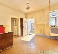 A spacious room with wooden flooring and windows in a family house, light streaming through the doors.