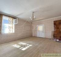 A spacious room in a family house with wooden flooring, wallpaper, and ceramic tiles.
