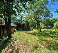 A garden by a family house in Gemerská Poloma, surrounded by fruit trees and a wooden fence.