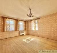A room in a family house with a wooden floor and wallpaper.