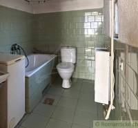 A bathroom in a family house with a bathtub, toilet, and washing machine with tiles.