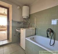 A family house bathroom with a bathtub, washing machine, and green tiles.