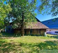 A family house in Gemerská Poloma with a garden, a tree, and a wooden annex.