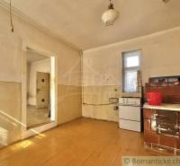 A room with a tiled stove and a cooker in a family house, wooden floor and simple furnishings.