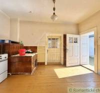 Traditional kitchen in a family house with a tiled stove and wooden plank flooring.